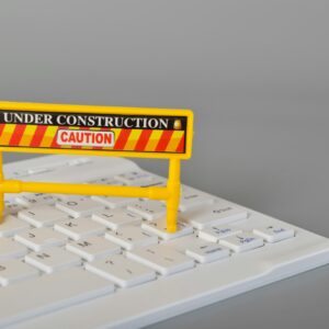Laptop keyboard and under construction sign. Website maintenance, programming, repair, coding.
